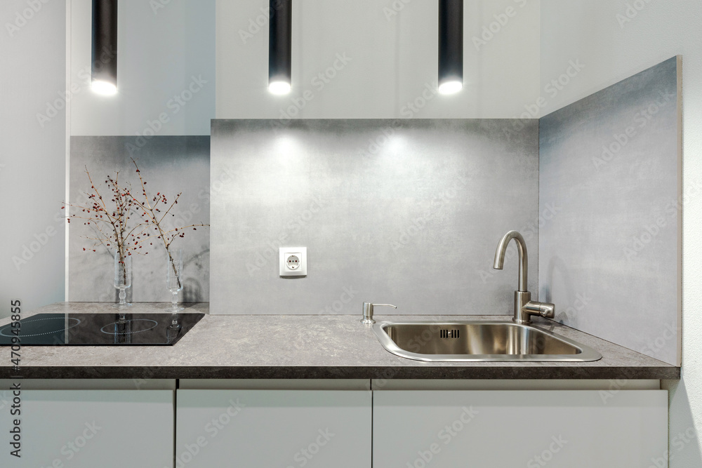 Fototapeta premium Minimalistic compact kitchen in a small apartment with elements of concrete, black and white