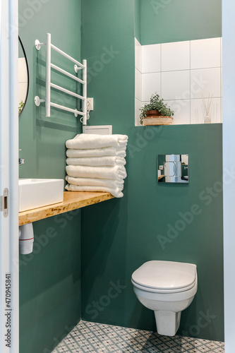 Minimalistic elegant design of bathroom in wormwood green color, installation, white bath. Wall paint for wet room using