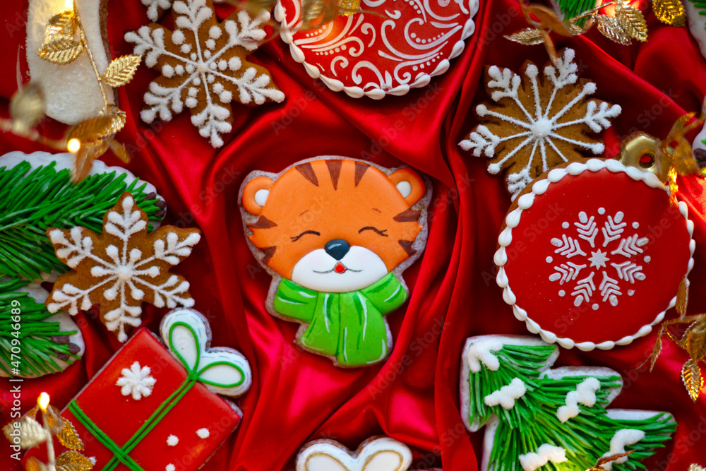 Banner for Christmas and New Year gingerbread tiger symbol Chinese zodiac calendar 2022 and gingerbread cookies snowflakes, Christmas trees, garlands on red silk fabric background