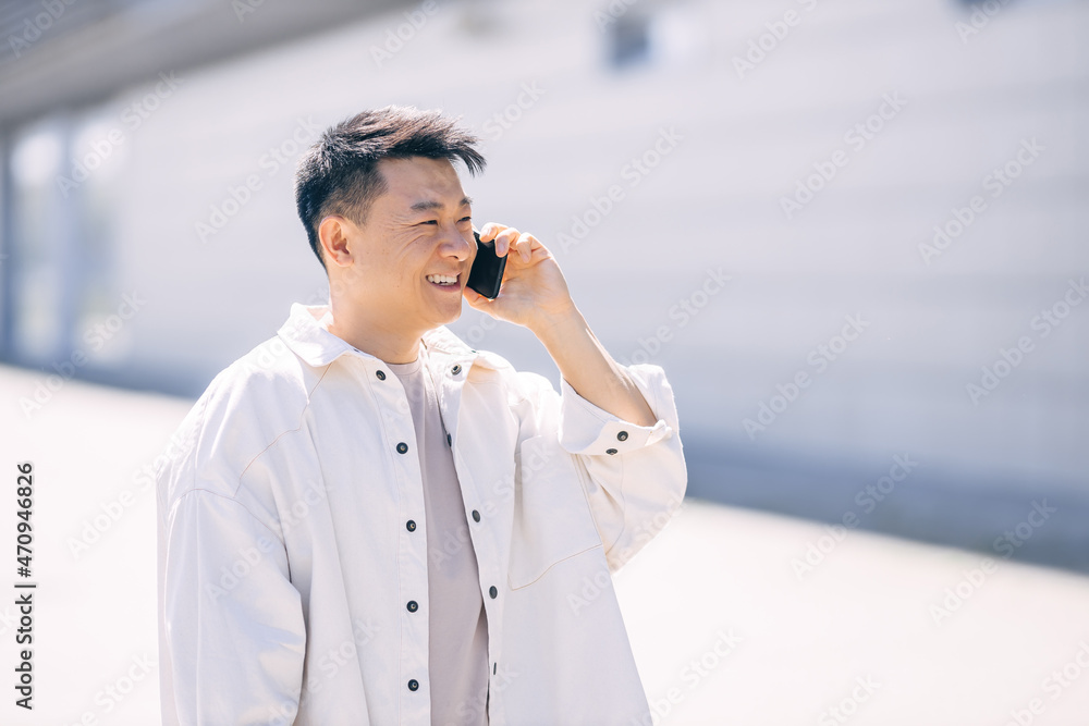 happy young man walking down the street looking away while talking on the phone happy young man walking down the street looking away while talking on the phone