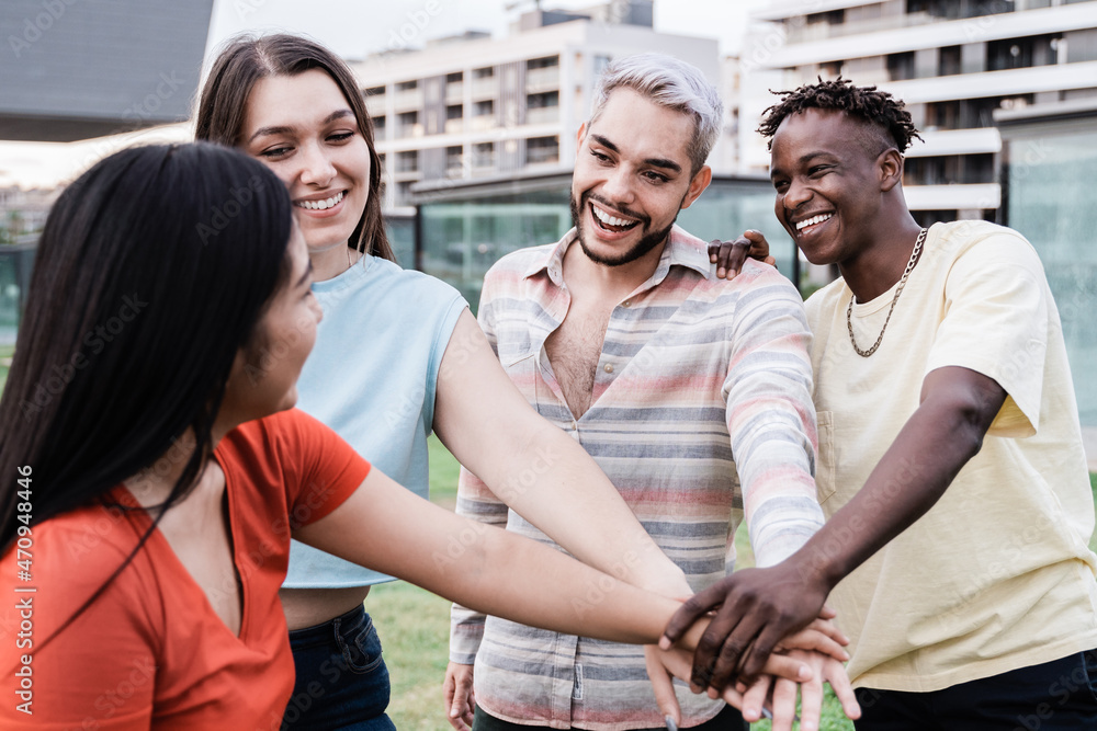 Young diverse group of people celebrating together stacking hands outdoor - Focus on gay man wearing makeup