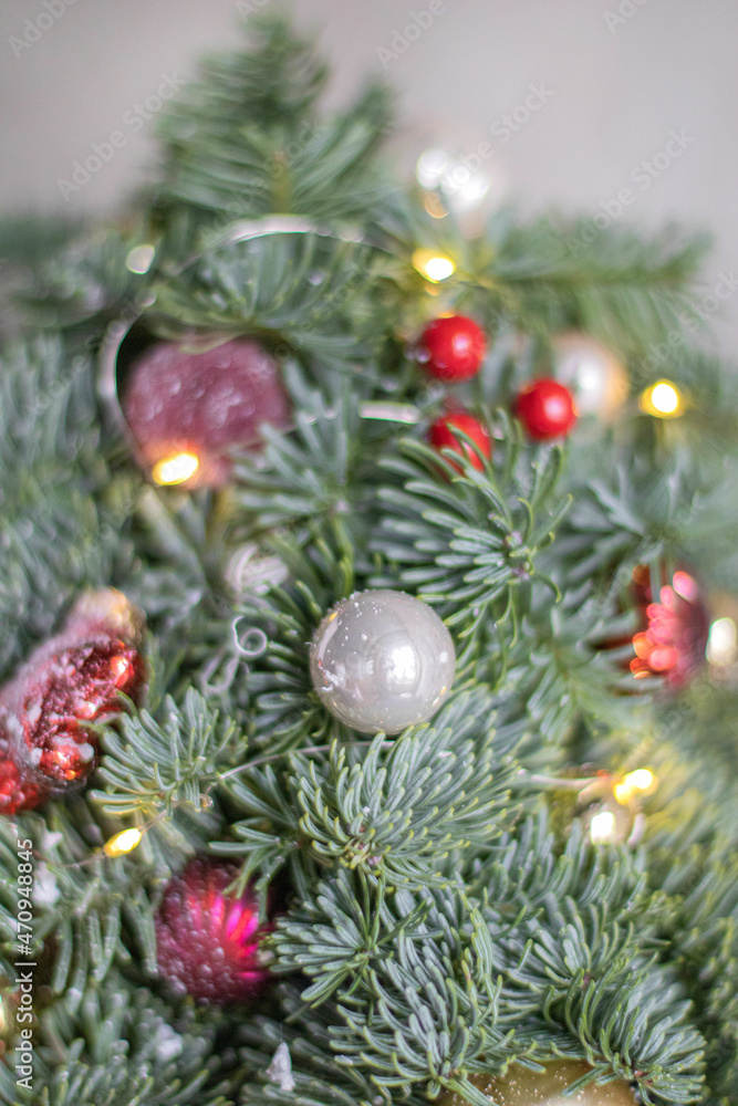 Small beautiful Christmas tree made of fresh Nobilis spruce, decorated red balls and pine cones, on dark table. Happy mood. Danish pine and fir, Nobilis.
