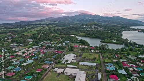 Beautiful aerial reveal of Tahiti iti volcanic mountains in French polynesia with local rural village. Pink dusk on a tropical island.  photo