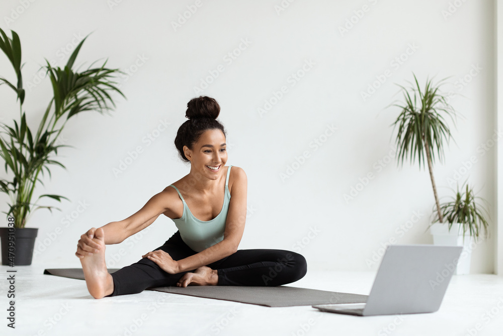 Home Sports. Young Beautiful Woman Training With Laptop, Stretching Leg Muscles Home Sports. Young Beautiful Woman Training With Laptop, Stretching Leg Muscles