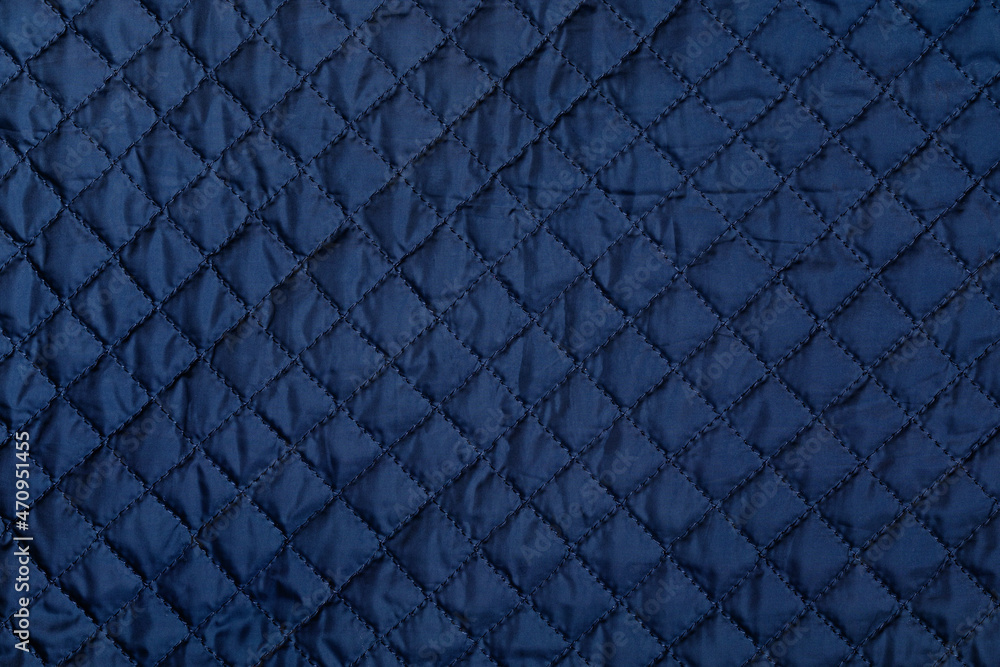 Blue texture of puffer, padded, down jacket. Background of urban winter outfit. Quilted pattern