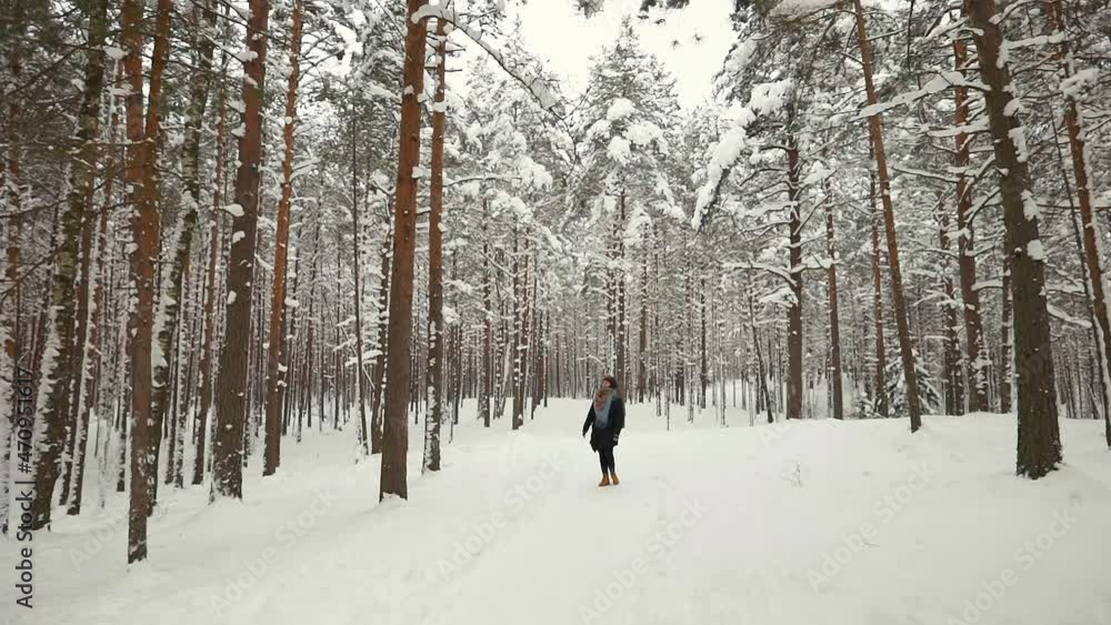Young woman walking through snowy pine alley in winter forest Young woman walking through snowy pine alley in winter forest