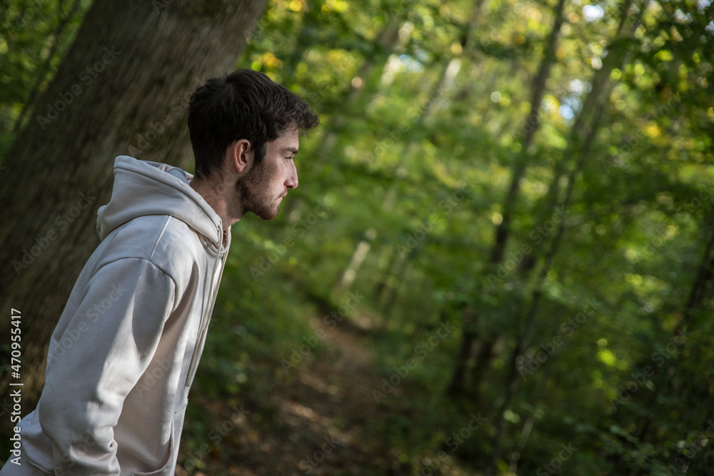 Jeune garçon pensif adossé contre un arbre en forêt. Sentiment de solitude et de tristesse. Jeune garçon pensif adossé contre un arbre en forêt. Sentiment de solitude et de tristesse.