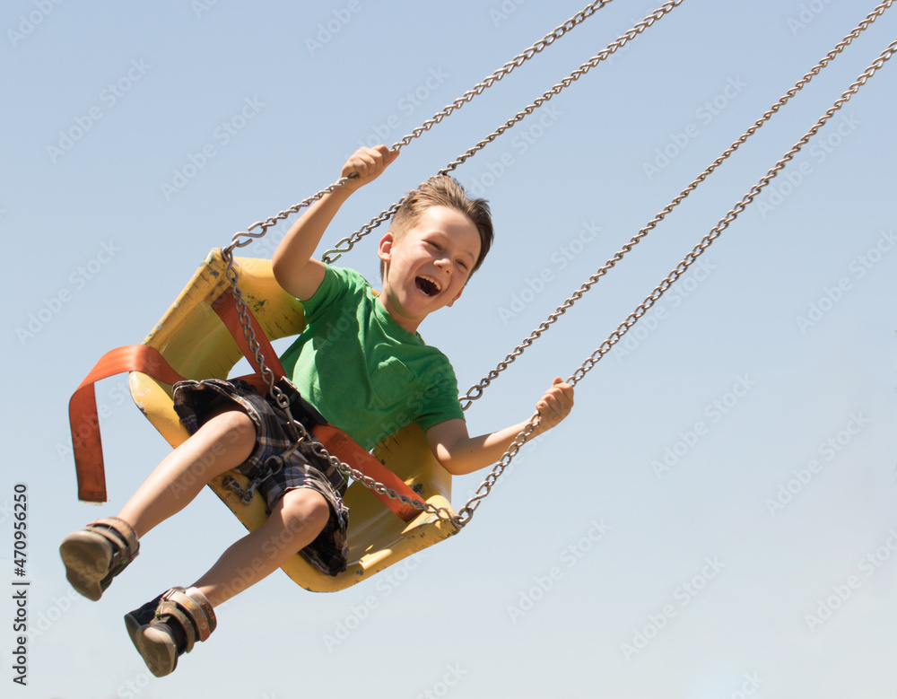 Joy thrill and fun are the emotions of a young boy swinging on a ride at the local carnival.