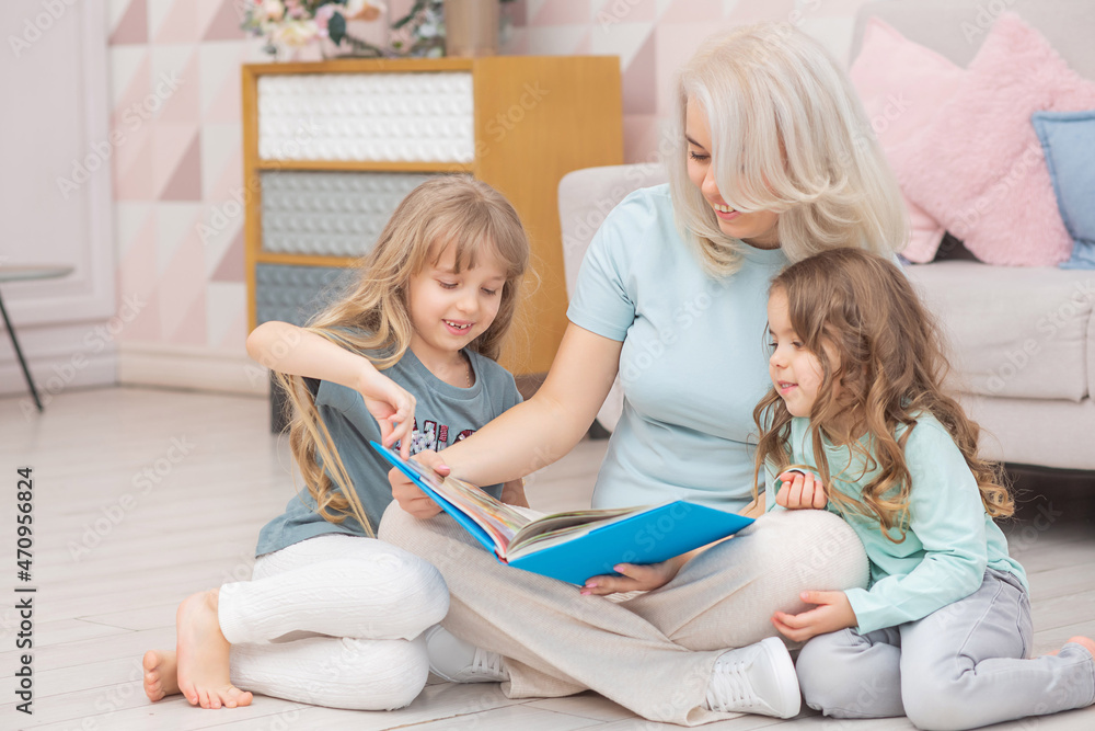 Obraz premium Caucasian mom reading a book to children sitting on the floor