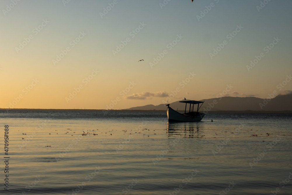 boat on the calm waters of the sea in the afternoon of a beautiful sunset, in the background, yellow and orange sky
