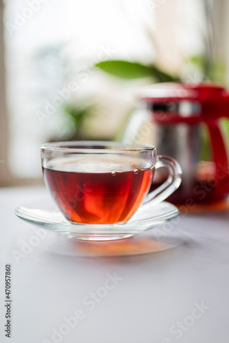 fragrant hot black English tea in a glass transparent cup with a teapot