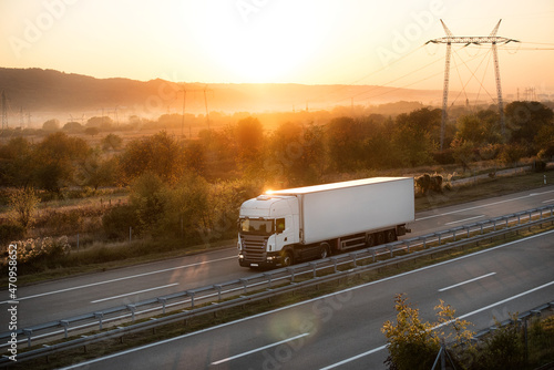 Big powerful truck along the highway. Highway transportation with hills and montains in the background
