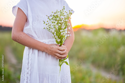 A hippy caucasian girl holding a bouquet of wildflowers in her hands