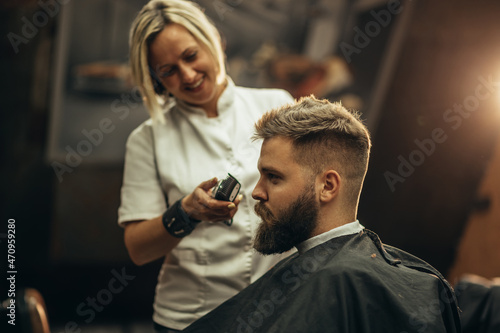 Young bearded man getting haircut by hairdresser