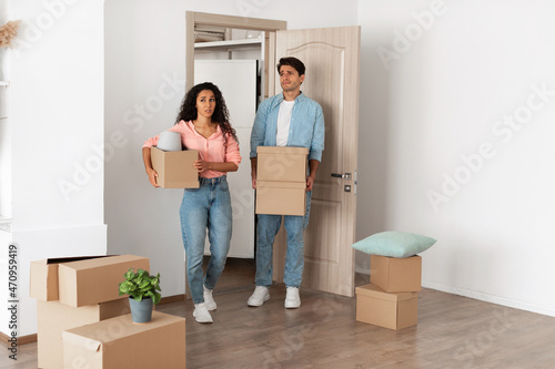 Slika na platnu Unhappy couple holding cardboard boxes, walking in new house