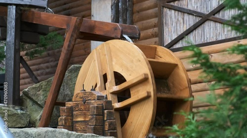 A decorative small watermill in the backyard spins under the spray of water. A water wheel under the guise of a waterfall. photo