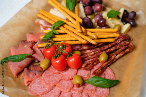 Different types of cheeses, meat and grapes.