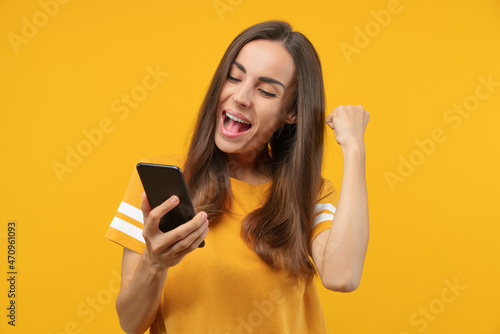 Portrait of euphoric soccer fan girl celebrating her favourite team victory and money win after betting at bookmaker's mobile application, making winner's gesture clenching her fist