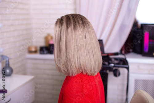 Female back with short straight ombre blonde hair in hairdressing salon