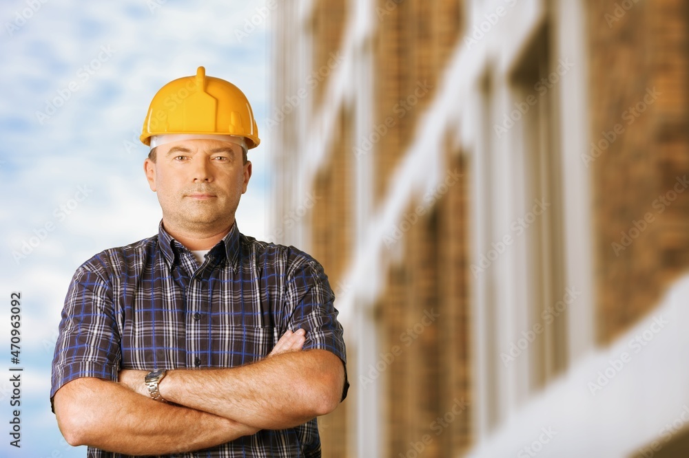 Male construction site manager standing wearing safety vest and helmet, thinking Male construction site manager standing wearing safety vest and helmet, thinking