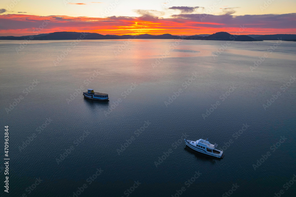 Naklejka premium Pink and purple sunrise waterscape with boats