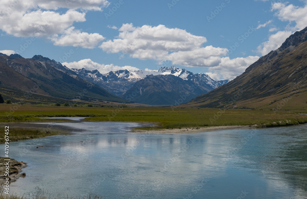 Scenic landscape view of Lake Hawea in New Zealand showing reflection of mountains in the water  mountains in the background blue sky with white puffy clouds horizontal postcard format room for type 