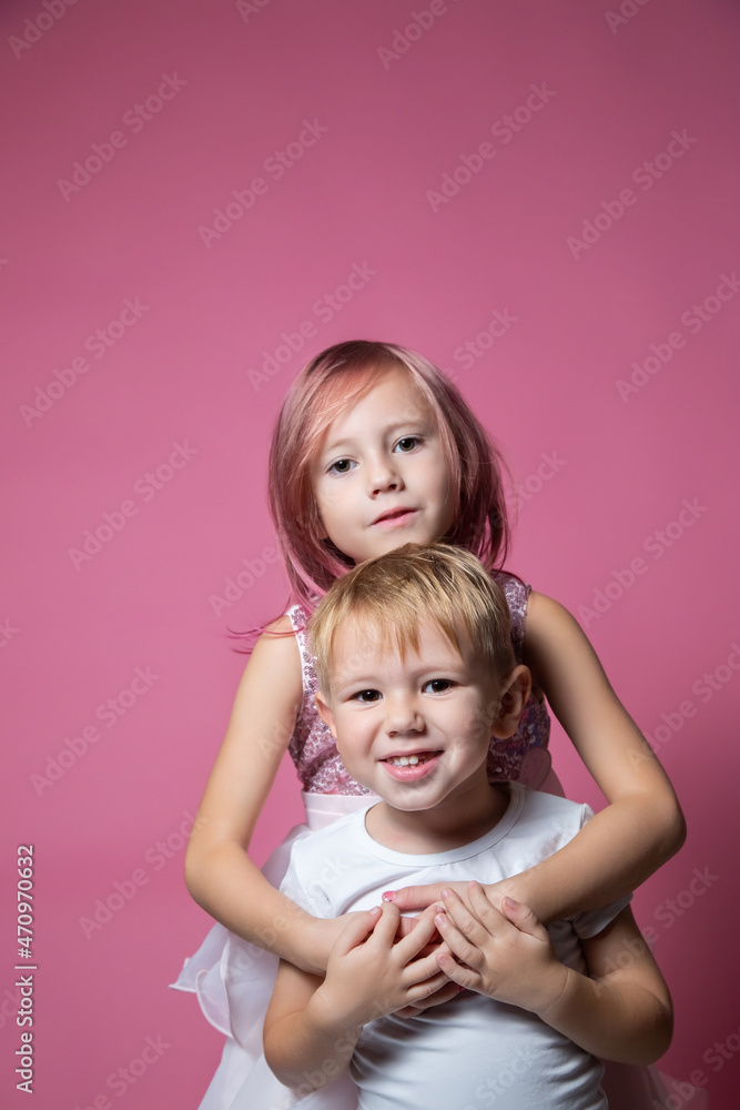 Caucasian brother and sister ,hugging on camera on pink background studio shot. Caucasian brother and sister ,hugging on camera on pink background studio shot.