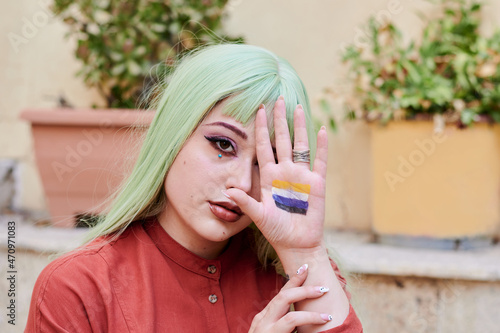 Person with green hair shows non-binary flag in the palm of her hand photo