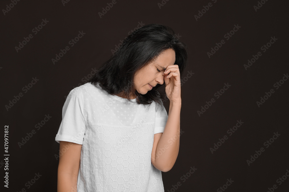 Mature woman suffering from headache on dark brown background Mature woman suffering from headache on dark brown background