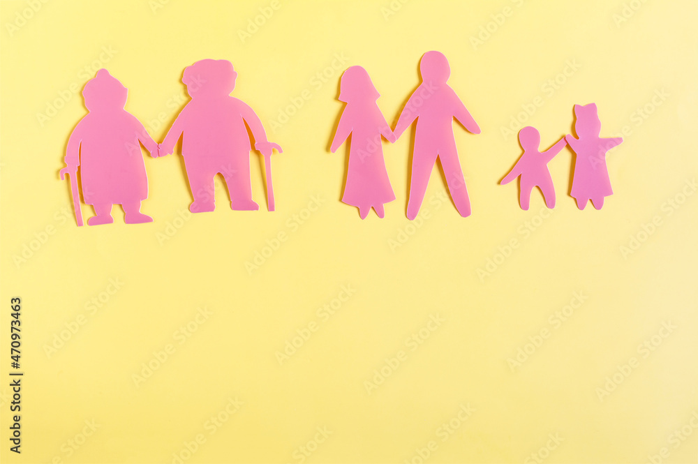 Colored cardboard figures of people of different generations on a yellow background Colored cardboard figures of people of different generations on a yellow background