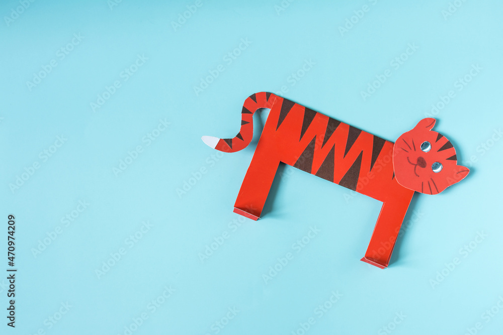 Origami orange tiger on a blue background copy space. The symbol of 2022 is a paper tiger close-up Origami orange tiger on a blue background copy space. The symbol of 2022 is a paper tiger close-up