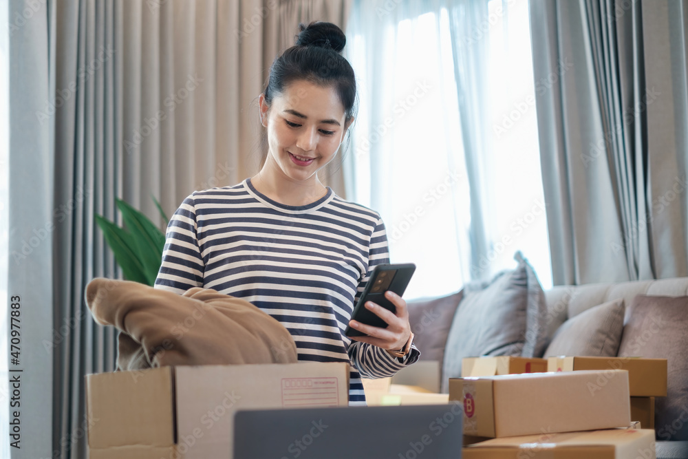 Asian small business owner checking order by smartphone at home office. Business retail market and online sell marketing delivery, SME e-commerce concept. Asian small business owner checking order by smartphone at home office. Business retail market and online sell marketing delivery, SME e-commerce concept.