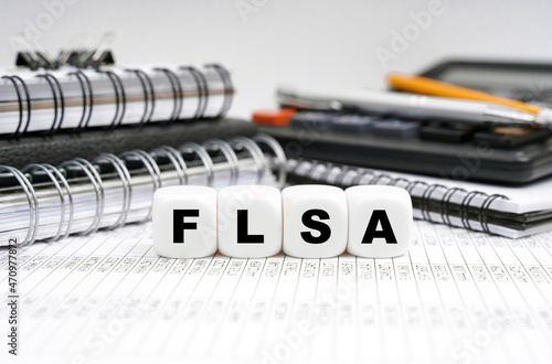 On the table, among office objects, cubes with the inscription - FLSA