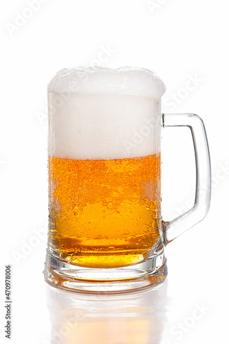 Light beer with thick head of foam in glass beer mug on white background