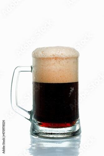 Dark beer with thick head of foam in glass beer mug on white background