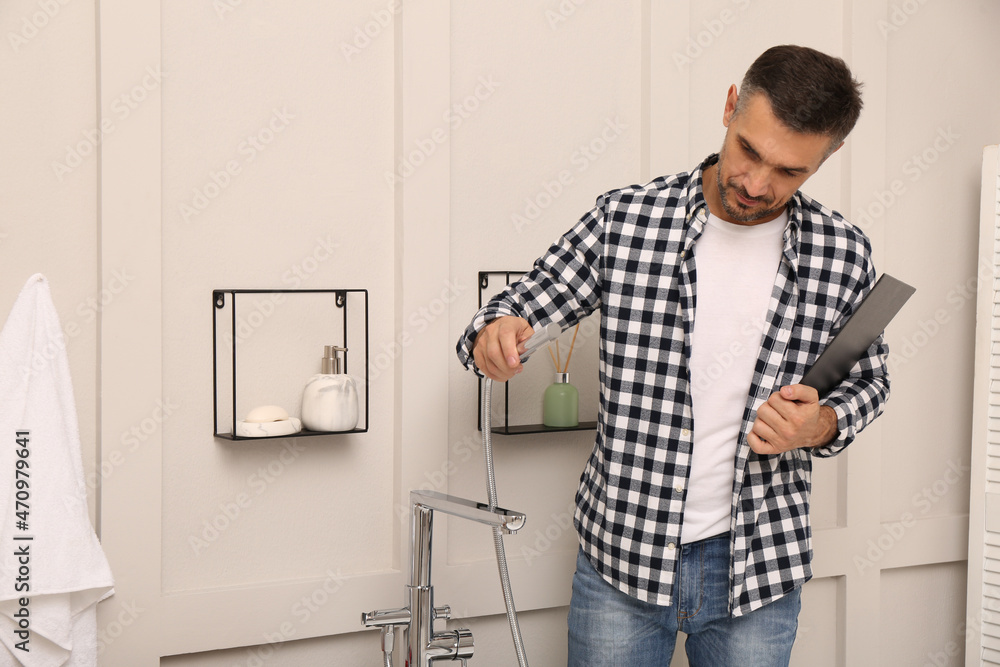 Plumber with clipboard checking water tap in bathroom Plumber with clipboard checking water tap in bathroom