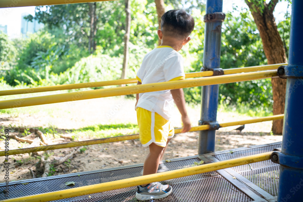 Little asian preschool boy playing in playground city public park