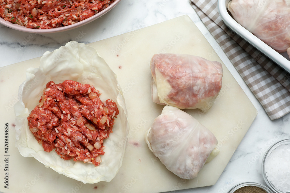 Preparing stuffed cabbage rolls on white marble table, flat lay