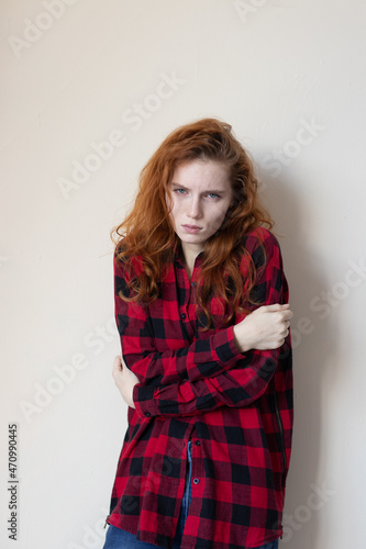 a young girl in a plaid shirt feels bad on a light background