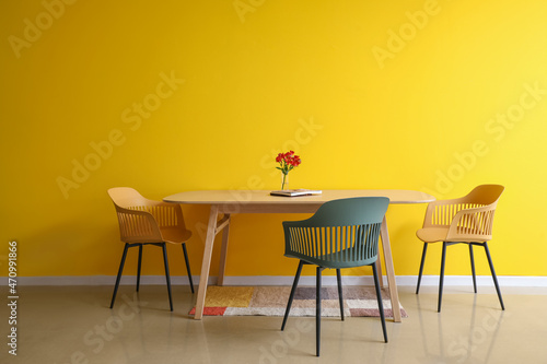 Dining table with flowers and magazine near color wall