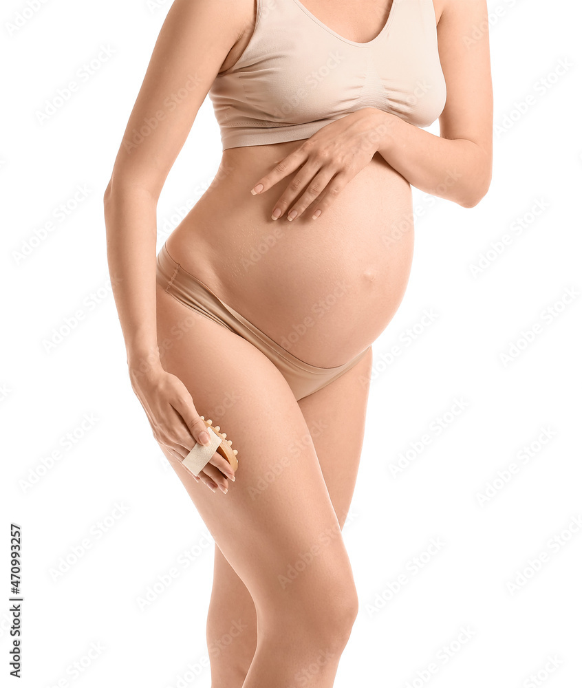 Beautiful pregnant woman with massage brush on white background