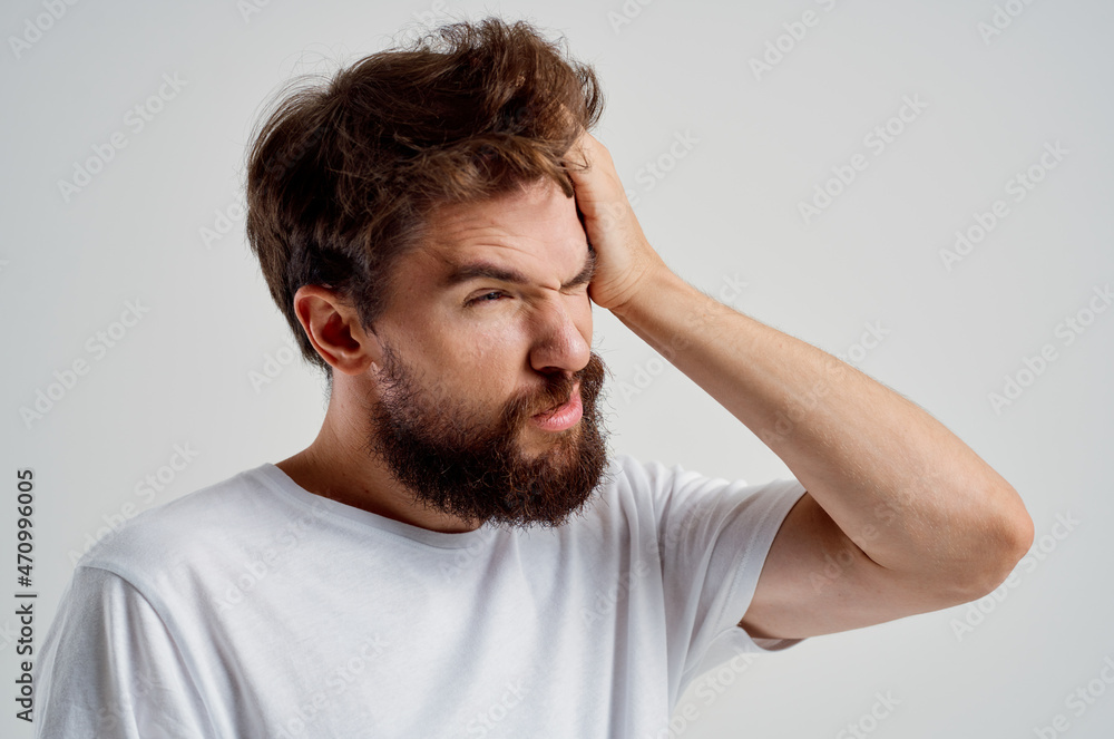 bearded man in a white t-shirt headache migraine problems light background bearded man in a white t-shirt headache migraine problems light background