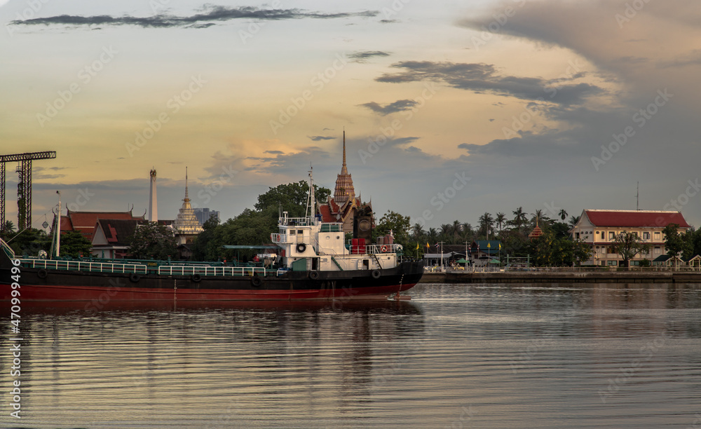 Fototapeta premium Bangkok, Thailand - Jul 31, 2021 : View of Chao phraya river has cargo ships docked in the middle river and the back is Wat Bangkrachaonok area. No focus, specifically.