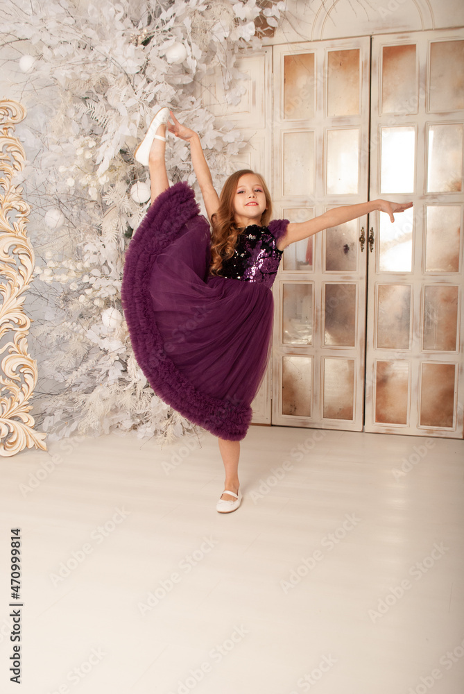 Obraz premium girl 8 years old on the holiday new year and Christmas 2022 dances in a dress against the background of a huge chandelier concept minimalism