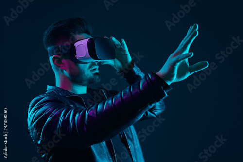 Man in VR glasses interacting with cyberspace in dark studio