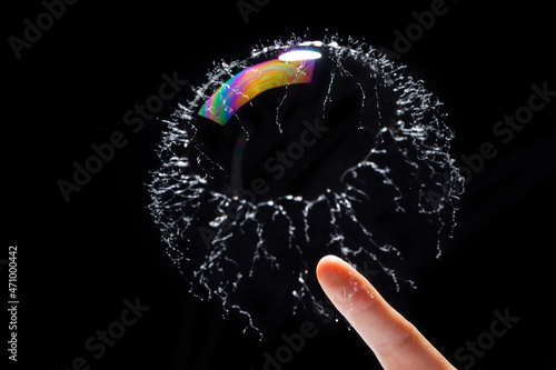 transparent soap bubble burst by a finger on black background. photo