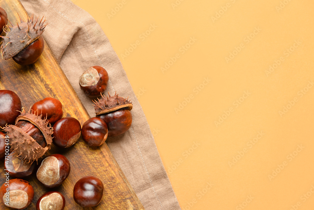 Wooden board with chestnuts on color background, closeup - obrazy, fototapety, plakaty 