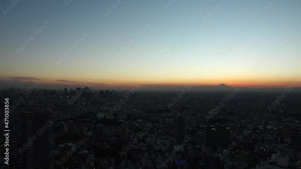 TOKYO, JAPAN : Aerial high angle sunrise CITYSCAPE of TOKYO and MOUNT FUJI. Golden sun rising behind mountains. Japanese city life and nature concept. Long time lapse shot night to morning. TOKYO, JAPAN : Aerial high angle sunrise CITYSCAPE of TOKYO and MOUNT FUJI. Golden sun rising behind mountains. Japanese city life and nature concept. Long time lapse shot night to morning.
