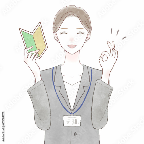 初心者マークを持ってOKサインを出すスーツを着た女性