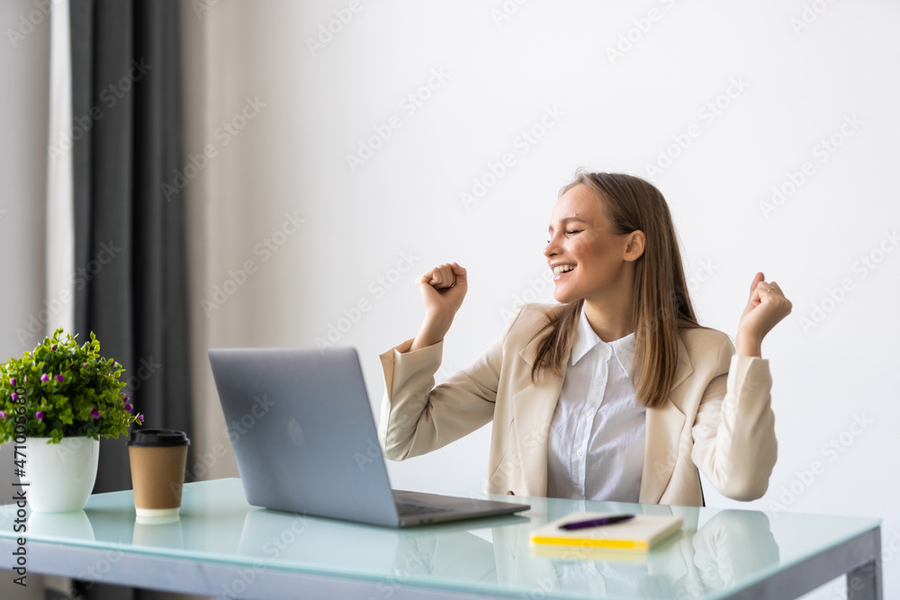 Excited young successful businesswoman triumphing in office